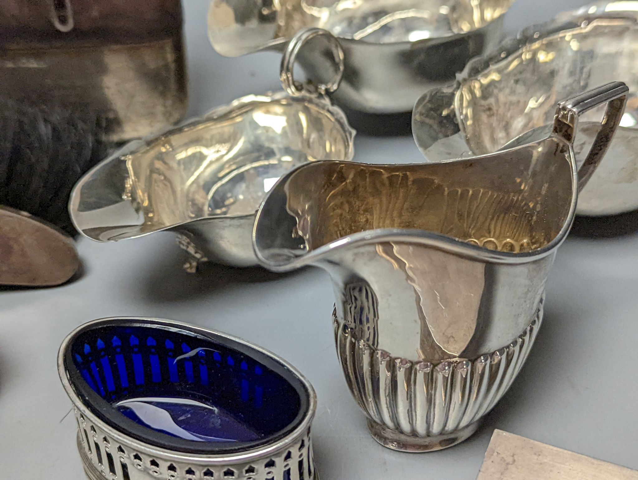 A group of assorted silver items including George V silver mounted hip flask(bruise), a pair of silver sauceboats(a.f.) one other sauceboat, sterling box, two silver cream jugs, cigarette box, salt, sugar tongs, brush an
